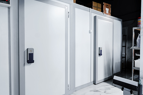 White walk-in cold storage doors with electronic handles in a commercial warehouse storage area