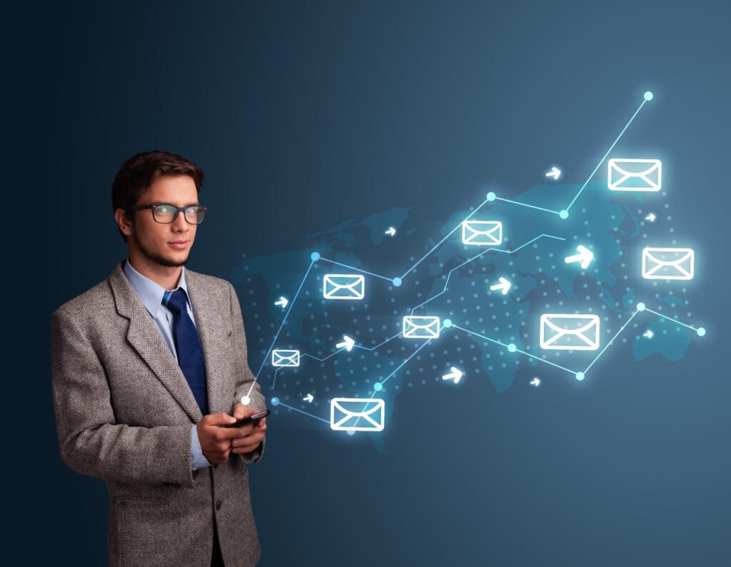 Young man in suit holding smartphone with glowing email icons and connected lines over a world map