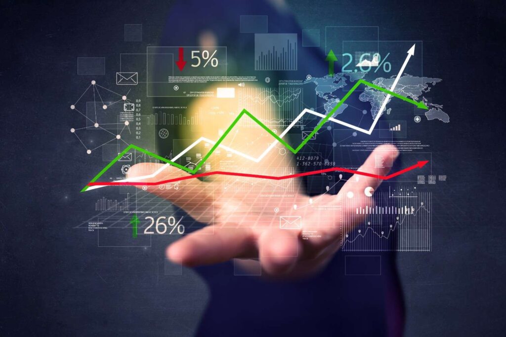 Outstretched hand presenting a transparent digital finance dashboard with green and red trend lines, charts, world map and percentage markers.