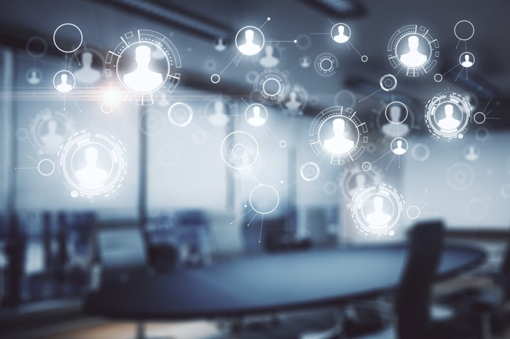 Blurry boardroom overlaid with glowing connected user icons and circular network graphics symbolising digital networking.