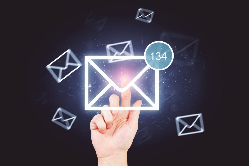 Hand pointing at a glowing email envelope icon with a blue notification bubble reading 134 against a dark background.