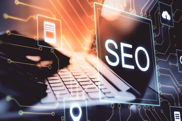 Laptop keyboard with hands typing and a glowing SEO label on screen, overlaid with digital icons and circuit lines.