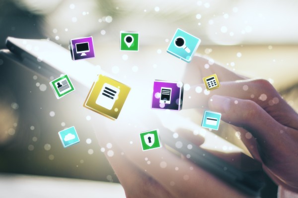 Hands holding a smartphone with colourful floating app icons (map pin, search, document, lock, cloud) against a soft bokeh background