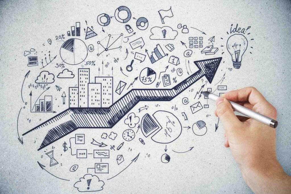 Hand sketching a bold upward arrow over doodled business charts, pie and bar graphs, icons and a lightbulb labelled idea.