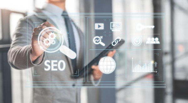 Business person tapping a transparent virtual SEO interface with magnifying-glass, gears, globe, link and analytics icons.